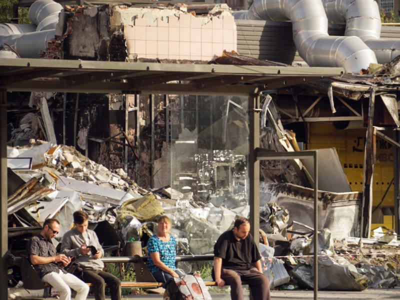 مدنيون يجلسون في محطة للحافلات بمدينة ماريوبو الأوكرانية  (أ ف ب)