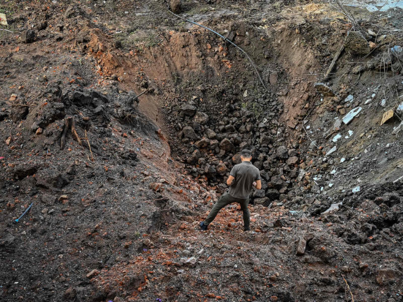 جندي أوكراني يعاين حفرة أحدثها صاروخ روسي قرب المقر المدمّر لمبنى إدارة خاركيف أمس (ا ف ب)