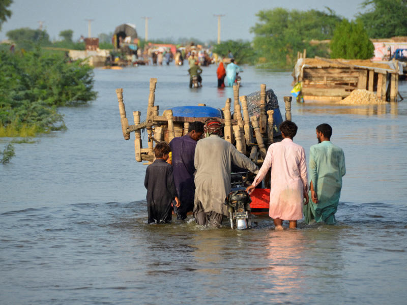 باكستانيون ينقلون ما تمكّنوا من إنقاذه وسط المياه في مدينة سوهباتور (رويترز)