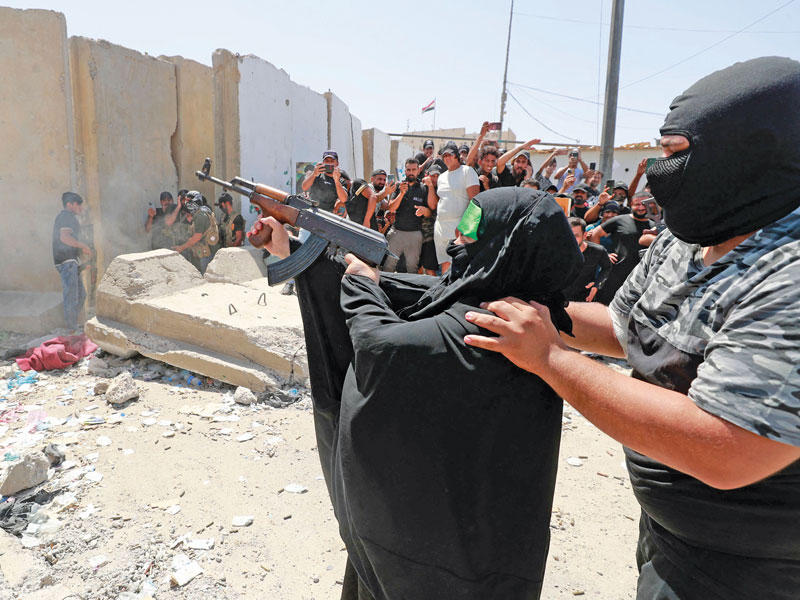 عنصر بسرايا السلام يساعد عراقية على إطلاق النار في المنطقة الخضراء (أ ف ب)