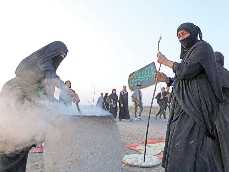 عراقيات يجهزن الطعام للزوار على الطريق من ذي قار إلى كربلاء  (أ ف ب)