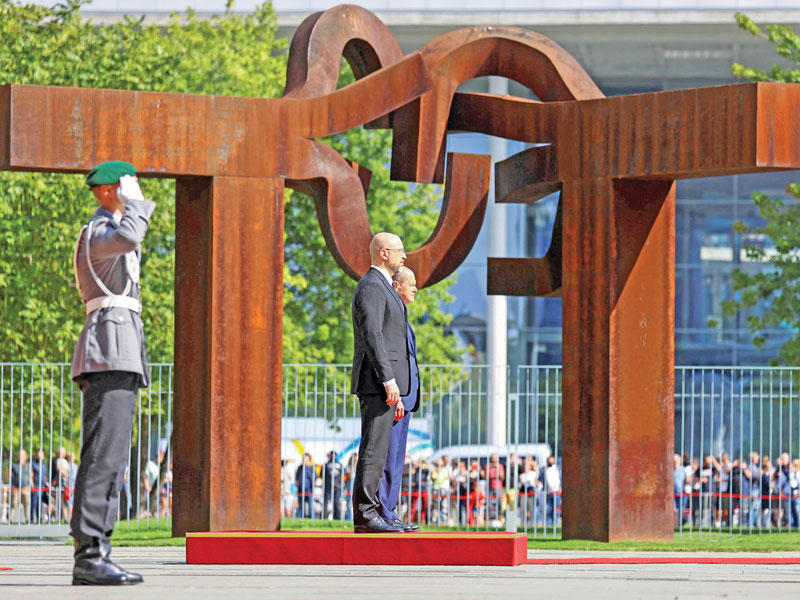 المستشار الألماني مستقبلاً رئيس الحكومة الأوكرانية لدى وصوله إلى برلين أمس (رويترز)