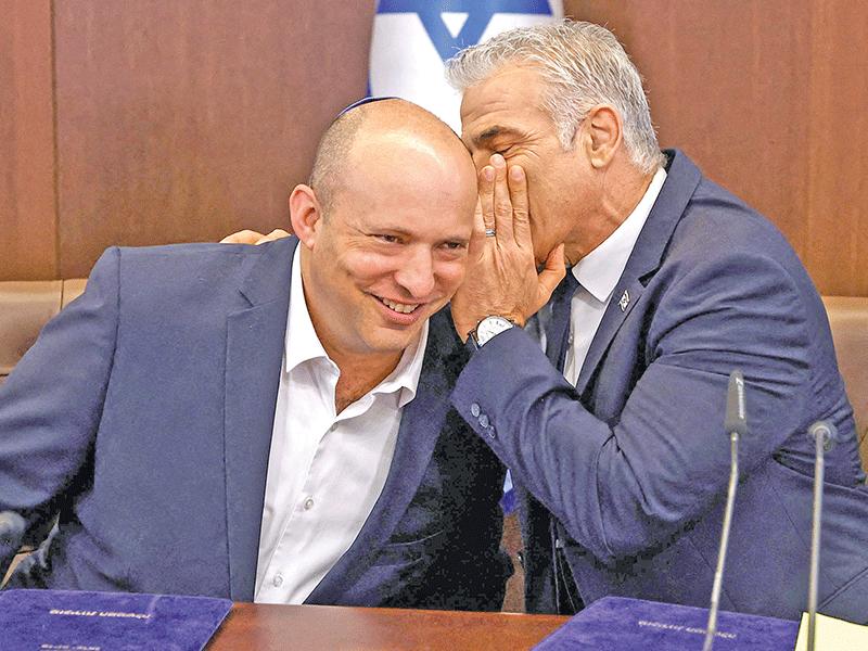 لابيد يهمس في أذن رئيس الوزراء السابق نفتالي بينيت خلال الاجتماع الحكومي بالقدس الغربية أمس    (أ ف ب)