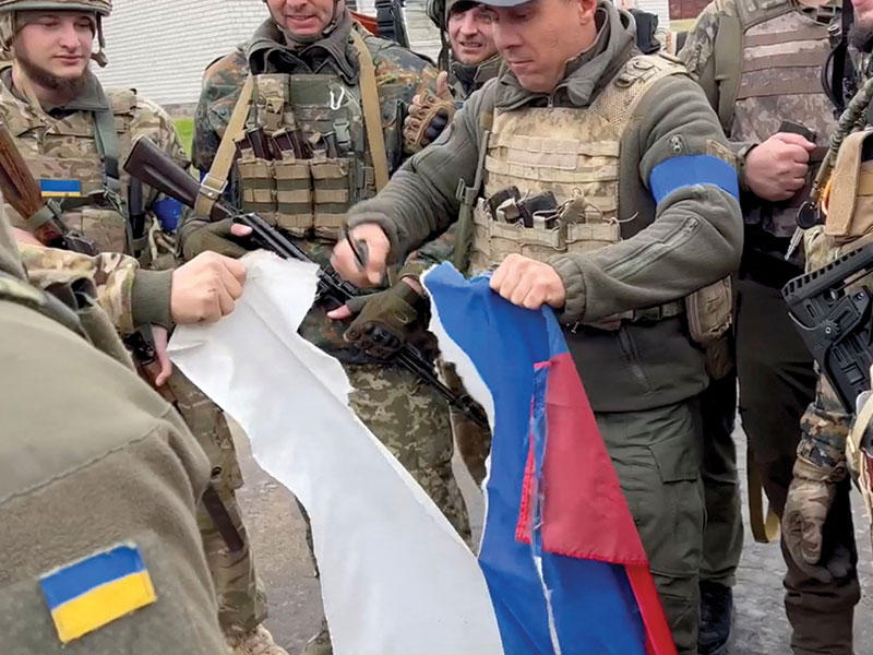 جنود أوكرانيون يمزقون علماً روسياً في خاركيف   (رويترز)