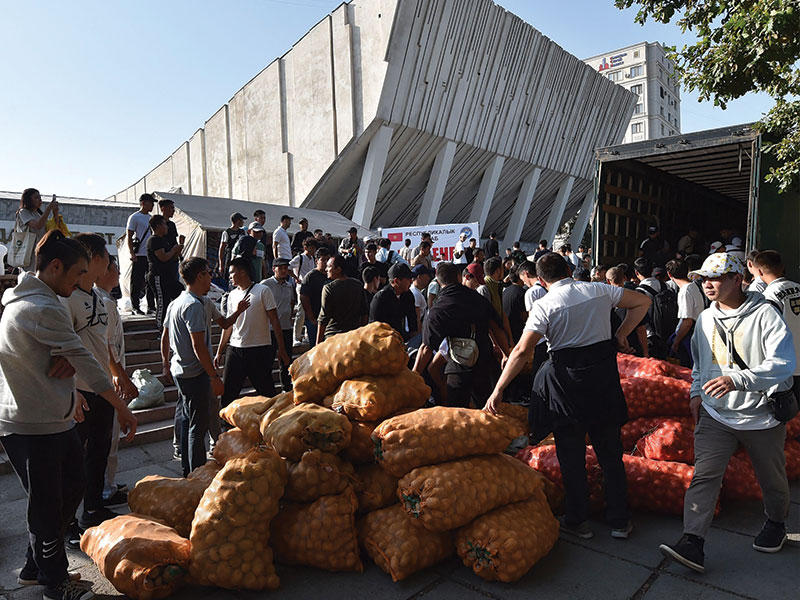 متطوعون يقدمون، أمس، مساعدات في بشكيك عاصمة قرغيزستان لنازحين من مناطق القتال على الحدود (أ ف ب)