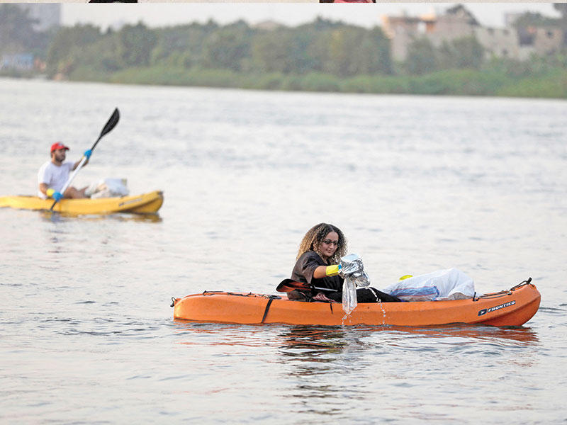 نشطاء مصريون يلتقطون عبوات بلاستيكية من النيل في الجيزة في إطار مبادرة بيئية (رويترز)