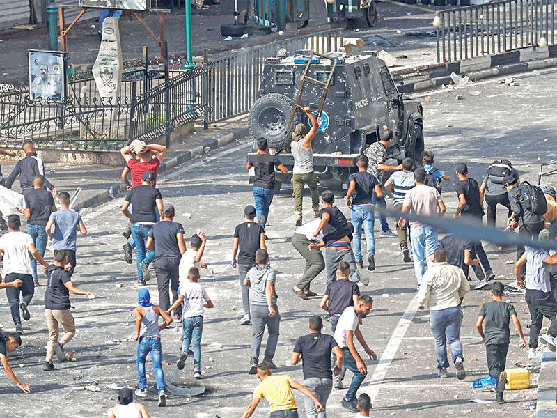 فلسطينيون يشتبكون مع قوات الأمن الفلسطينية في نابلس أمس (رويترز)