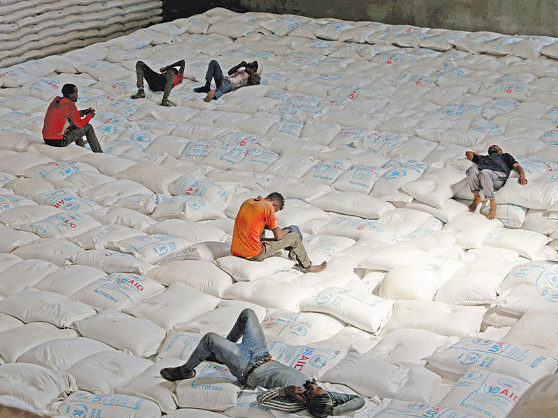 عمال يرتاحون خلال تفريغ شحنة حبوب أرسلت من أوكرانيا إلى إثيوبيا في مخزن خاص لمنظمة الغذاء العالمية بمدينة أداما الإثيوبية (رويترز)