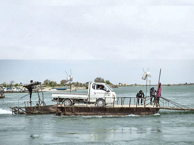 مركبة تُنقل على منصة على نهر الفرات في مدينة الرقة شمال سوريا