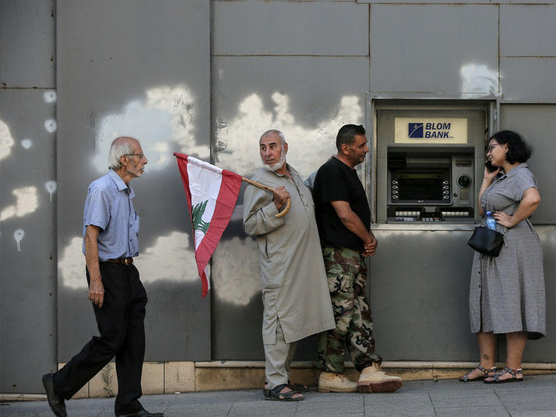مواطنون أمام آلة سحب النقود في بيروت أمس مع فتح المصارف أبوابها بعد إضراب استمر أياماً (د ب أ)