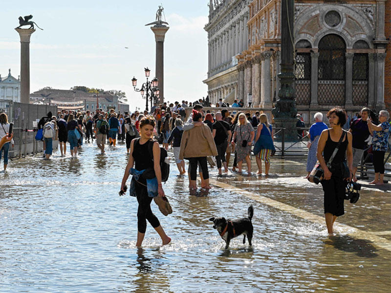 سياح يلتقطون صوراً بساحة بازيليك سانت مارك في فينيسا المغمورة بالمياه بسبب فيضان (أ ف ب)