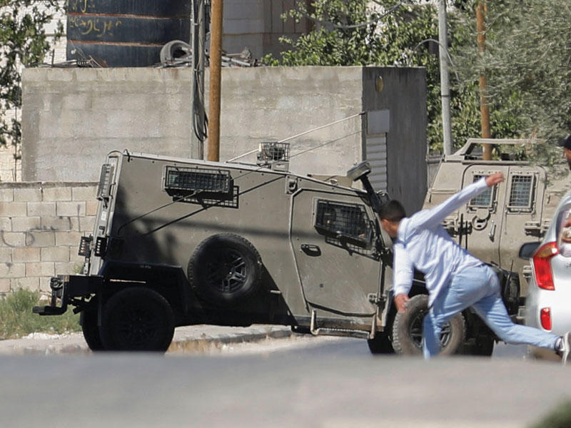 شبان فلسطينيون يتصدون بالحجارة لدورية إسرائيلية في جنين أمس (رويترز)