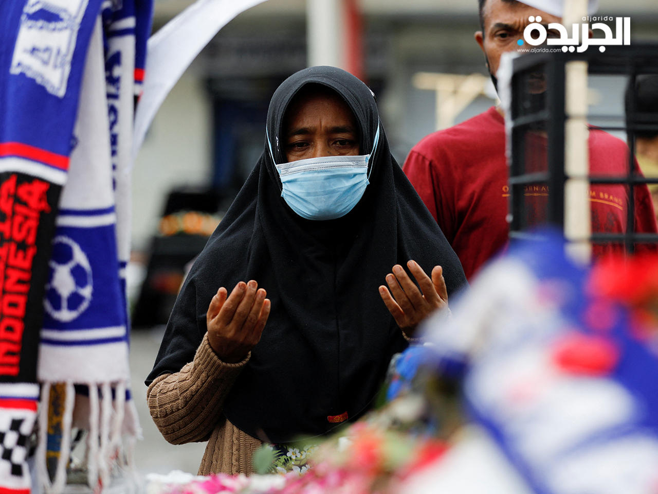 سيدة تقرأ الفاتحة وهي تقدم العزاء في ضحايا ملعب كانجوروهان في إندونيسيا