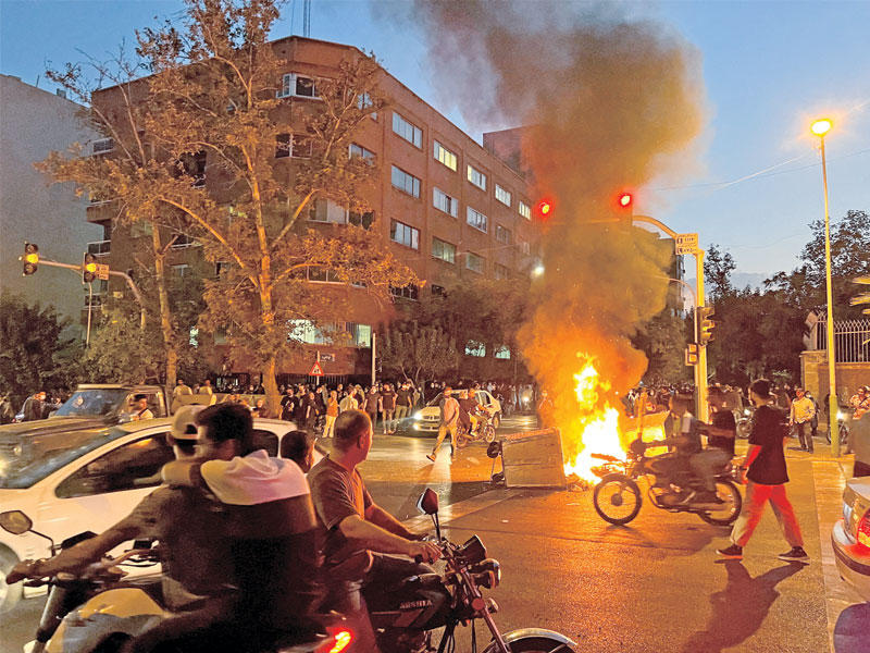 محتجون يشعلون النار بحاوية قمامة وسط طهران (رويترز)