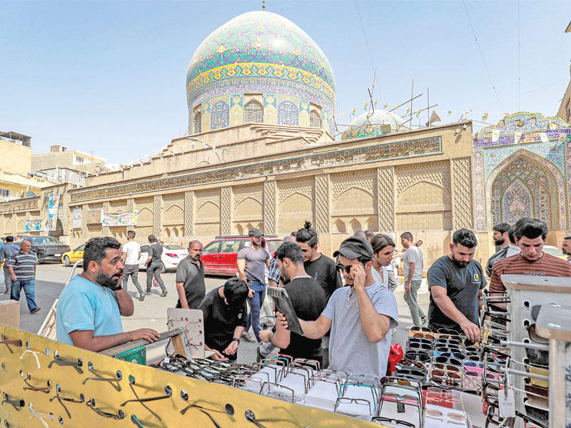 عراقيون أمام جامع مدرسة الأحمدية في شارع الميدان ببغداد أمس