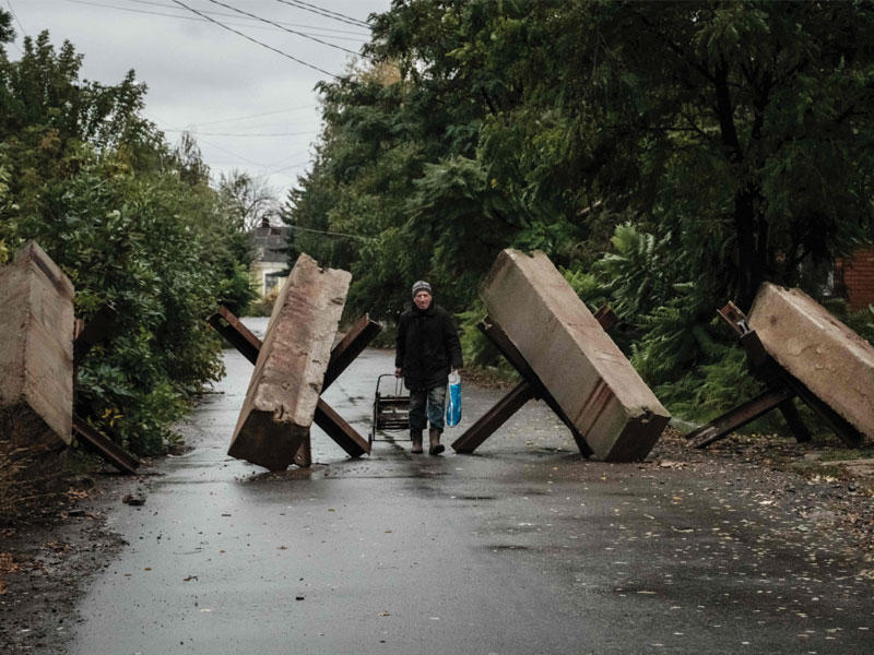 رجل يمر أمام عوائق مضادة للدبابات في مدينة باخموت بدونيتسك التي تحاول روسيا السيطرة عليها (أ ف ب)