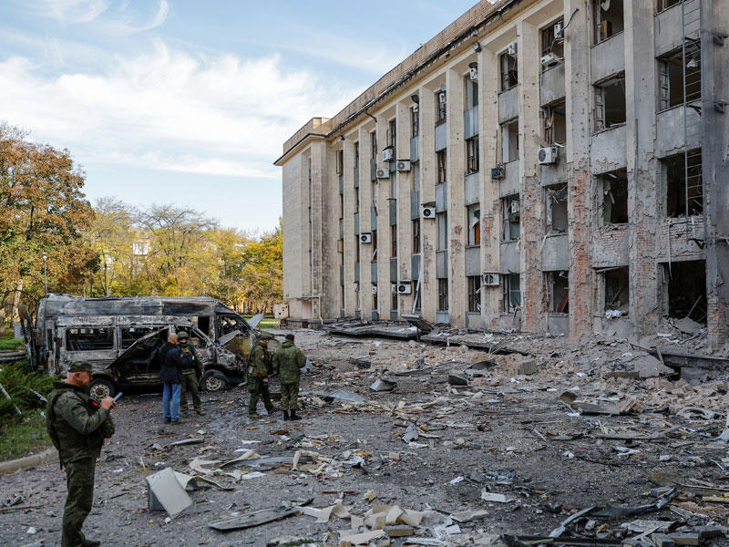 جنود موالون لروسيا يعاينون مبنى حكومياً تعرّض للقصف في دونيتسك أمس (رويترز)