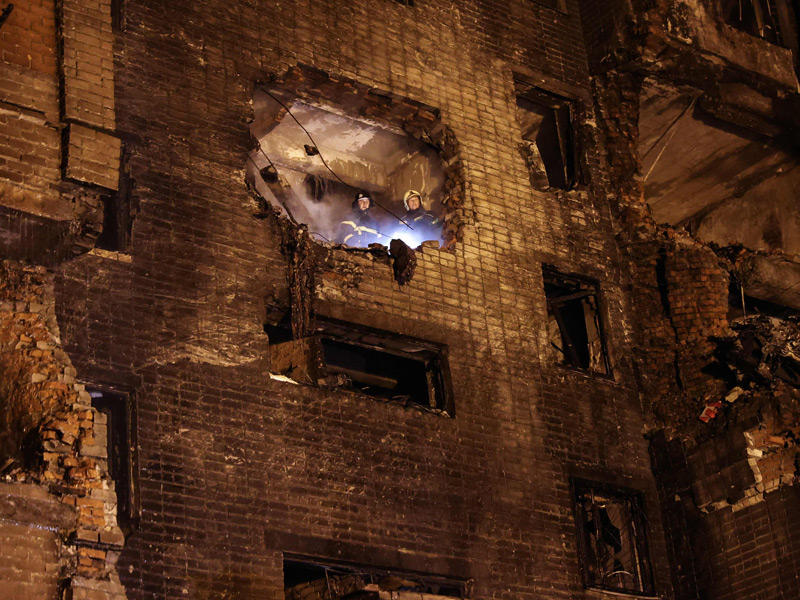 رجلا إطفاء ينظران من فجوة في شقة سكنية أحدثها انفجار تحطّم مقاتلة «سوخوي» بمدينة ييسك الروسية (أ ف ب)