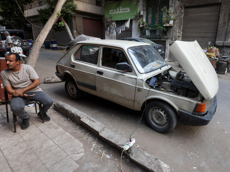علي السعيد الذي نجح في تحويل سيارة من عام 1985 إلى سيارة كهربائية يقوم بشحن سيارته في القاهرة (رويترز) 