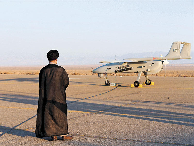 رجل دين شيعي ينظر إلى مسيّرة خلال مناورات عسكرية (رويترز)